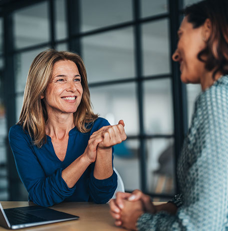 Zwei Gesch&auml;ftsfrauen tauschen sich im B&uuml;ro aus und vermitteln pers&ouml;nliche Beratung, Zusammenarbeit und strategische Abstimmung.