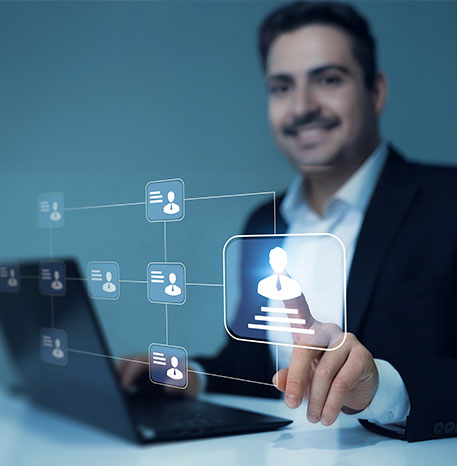 Eine Person bedient ein Laptop, während in der Luft digitale Symbole von Nutzerprofilen eingeblendet sind. Die Person zeigt auf ein hervorgehobenes Profilbild, das eine strukturierte Darstellung von Bewerberdaten symbolisiert.