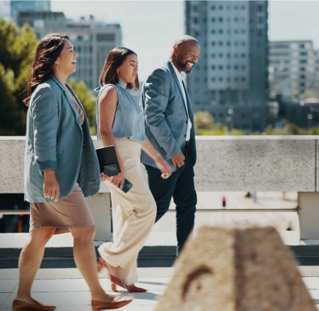 Drei Personen spazieren vor dem Hintergrund der Stadtlandschaft.